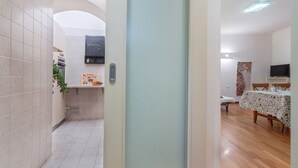 Un pasillo que conduce a un comedor con una mesa, sillas, un televisor y una puerta con un cartel de bienvenida.