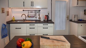 A kitchen with white cabinets, a sink, and a countertop with a cutting board and vegetables. - Vacation with dog, and without dog (Varel)