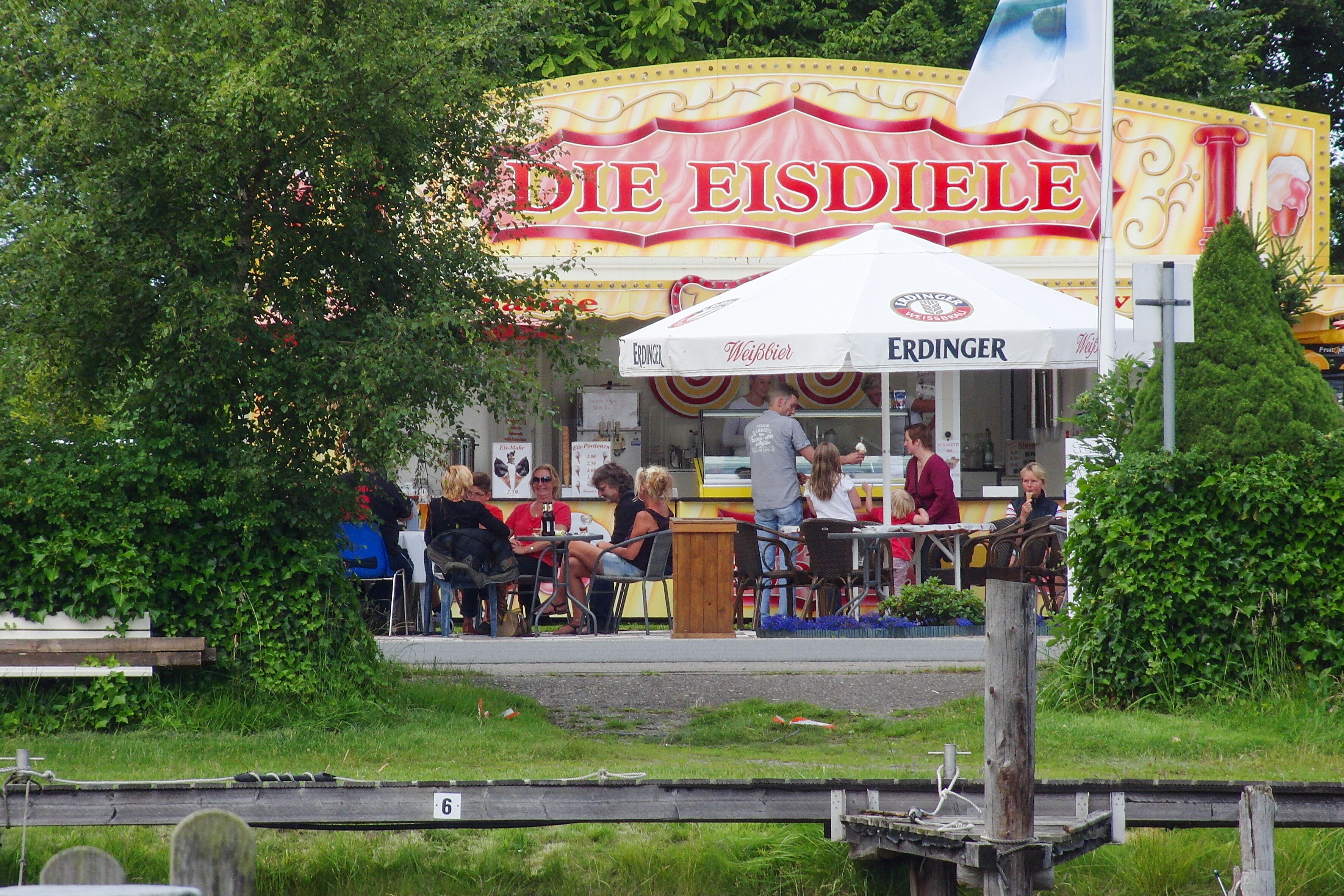 Un stand de nourriture appelé « Die Eisdiele », avec un parasol blanc et une enseigne.