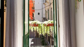 A narrow doorway leading to a balcony with a view of a red building and greenery. - Arechi Room (Salerno)