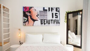 A bedroom with a bed, a wall-mounted artwork, a bedside table, and a mirror. - Arechi Room (Salerno)
