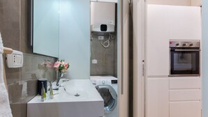 Un baño moderno con lavamanos, espejo y lavadora.