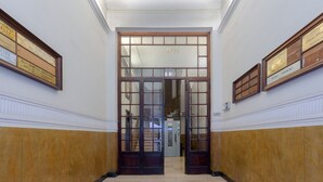 Un pasillo con puertas dobles, certificados enmarcados en las paredes y suelo de mármol.