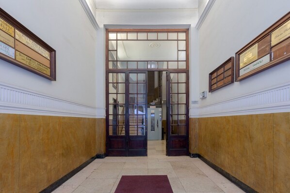 Un pasillo con puertas dobles, certificados enmarcados en las paredes y suelo de mármol.