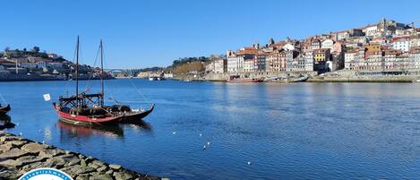 Un puerto con barcos, un muelle de piedra y un horizonte urbano con edificios de colores.