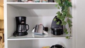 A kitchen with a coffee maker, toaster, kettle, and a plant on the shelf. - Cais de Gaia Historic Loft (Vila Nova de Gaia)