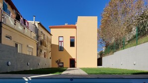 A swimming pool with a clear blue water surface, surrounded by buildings with balconies and a tree with autumn leaves. - Cais de Gaia Historic Loft (Vila Nova de Gaia)