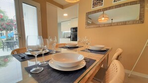 A dining area with a glass table, white plates, and wine glasses set for a meal. - An oasis in the center of Corralejo! (Corralejo - Fuerteventura)