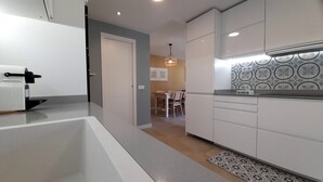 A modern kitchen with white cabinetry, a built-in oven, and a patterned backsplash. - An oasis in the center of Corralejo! (Corralejo - Fuerteventura)