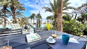 A wooden table with a white cup, a blue mug, and a tray of snacks. - An oasis in the center of Corralejo! (Corralejo - Fuerteventura)