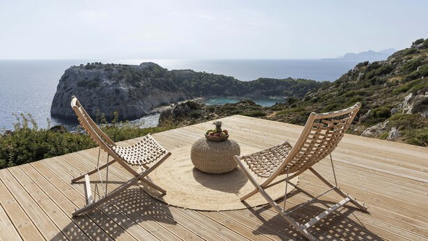 A wooden deck with two wicker chairs and a round table with fruit. - Pristine Seaview Villa , with 5-Star Resort Access (Faliraki)