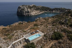 Una piscina al aire libre, una piscina con borde infinito, tumbonas