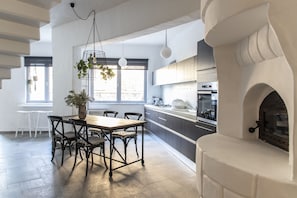 Une cuisine moderne dotée d’un four encastré, d’un coin repas avec une table et des chaises en bois, et de plantes suspendues.