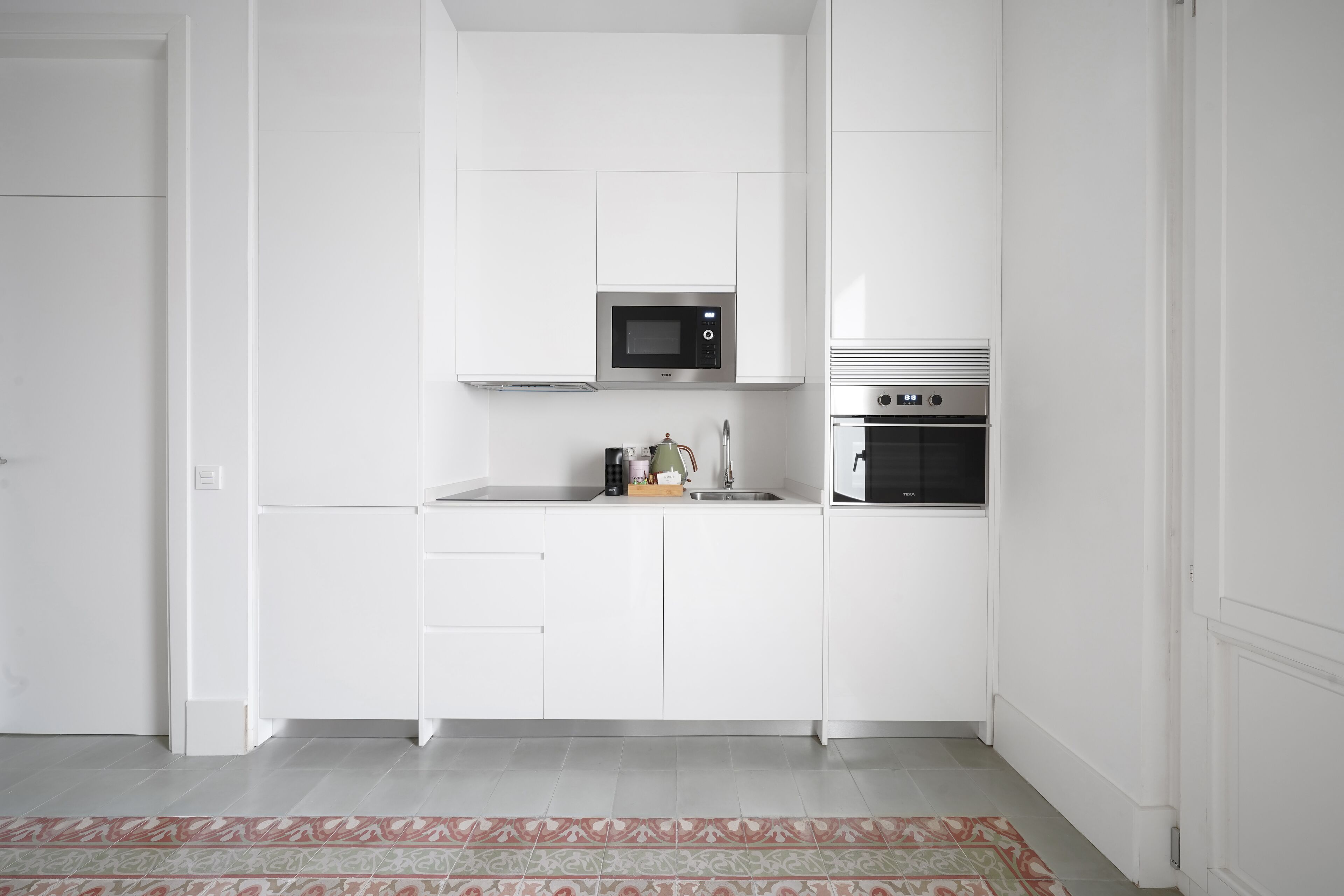 Une cuisine moderne avec des meubles blancs, un four à micro-ondes, un évier et un four traditionnel.