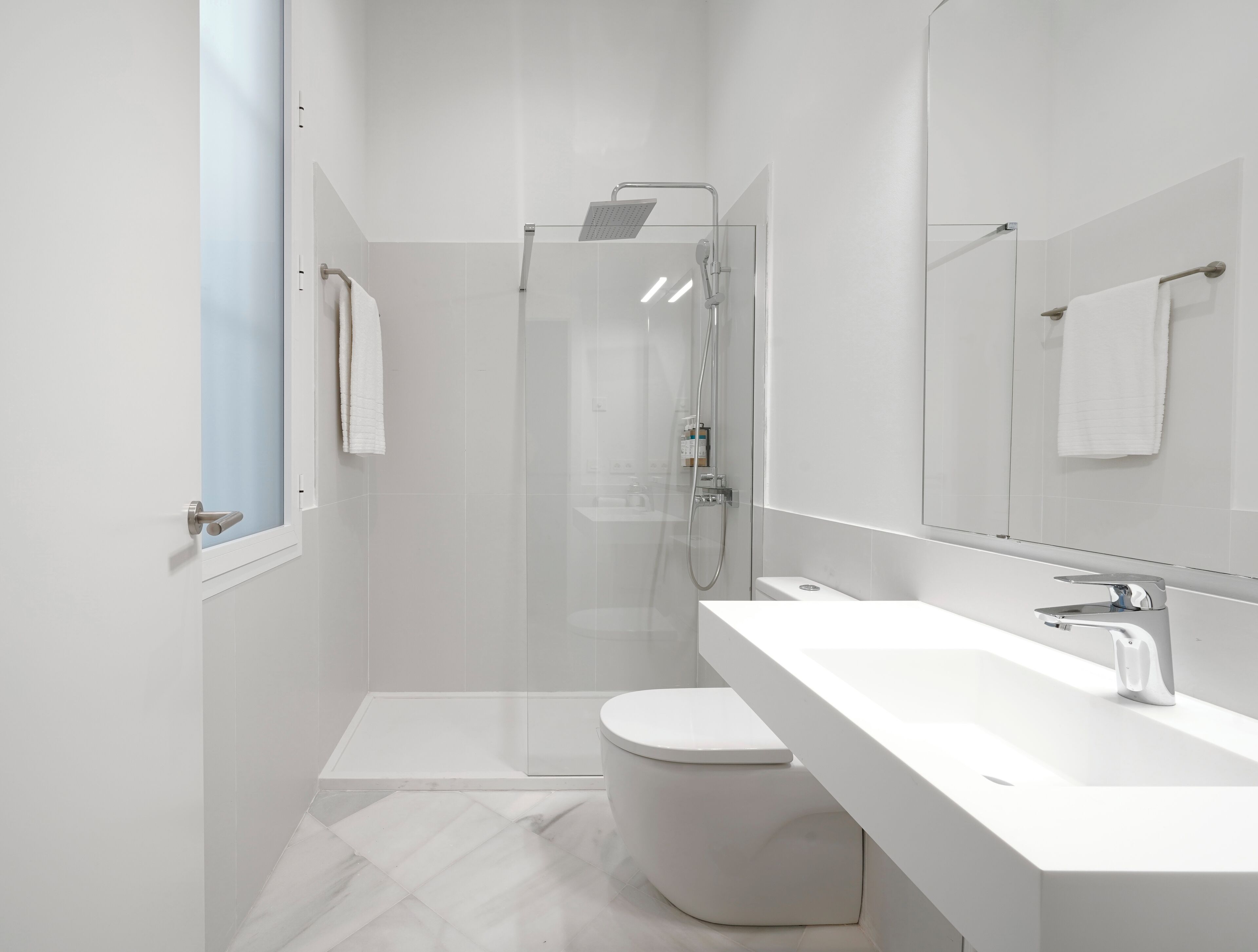 Et moderne badeværelse med bruser, toilet og håndvask.