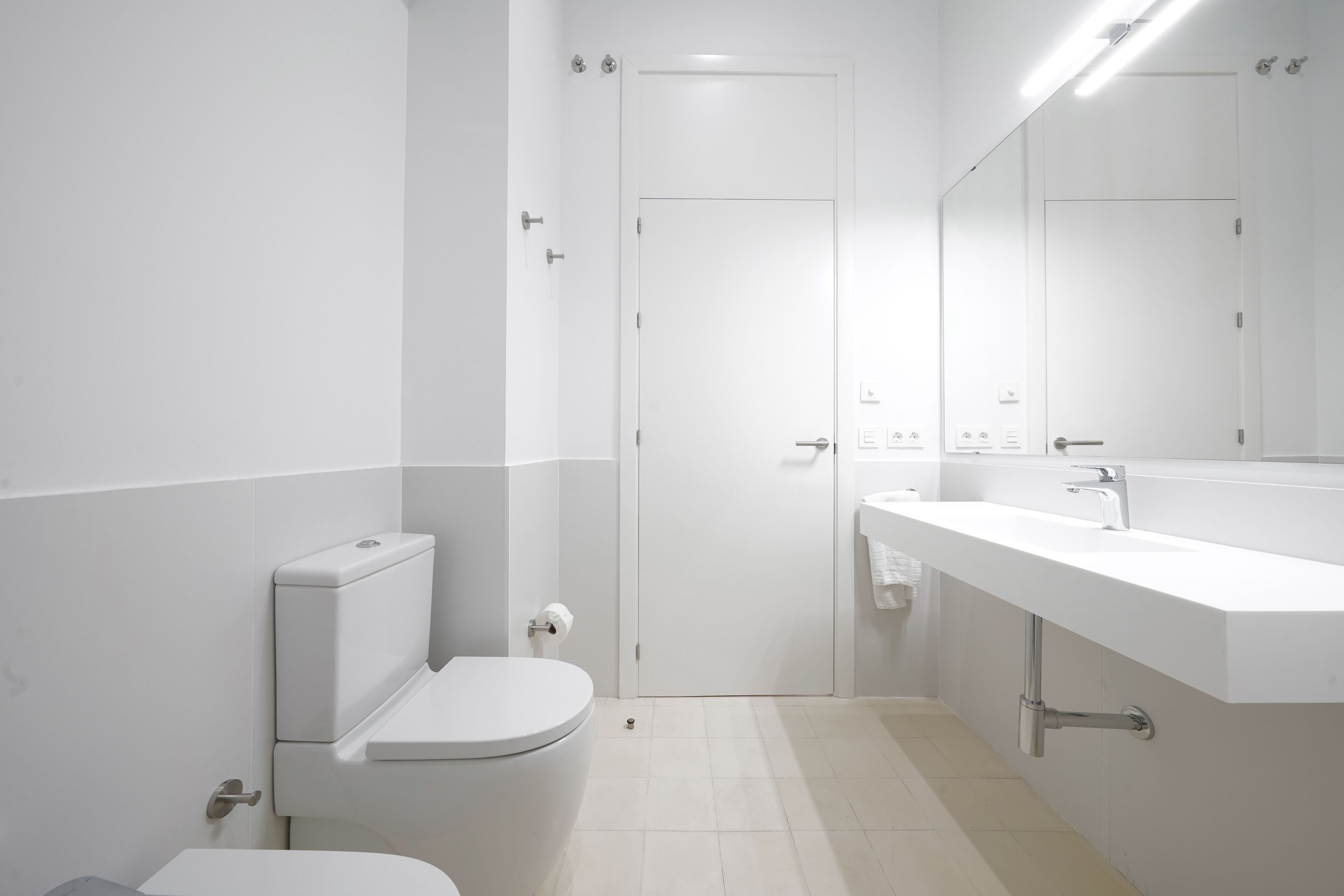 A modern bathroom with a toilet, sink, and mirror.