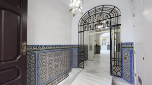 A hallway with a dark wooden door, white walls, and blue patterned tiles. - Numa Seville Solea (Seville)