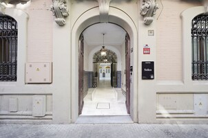 Uma entrada em arco com soalho em azulejos que dá para um corredor.