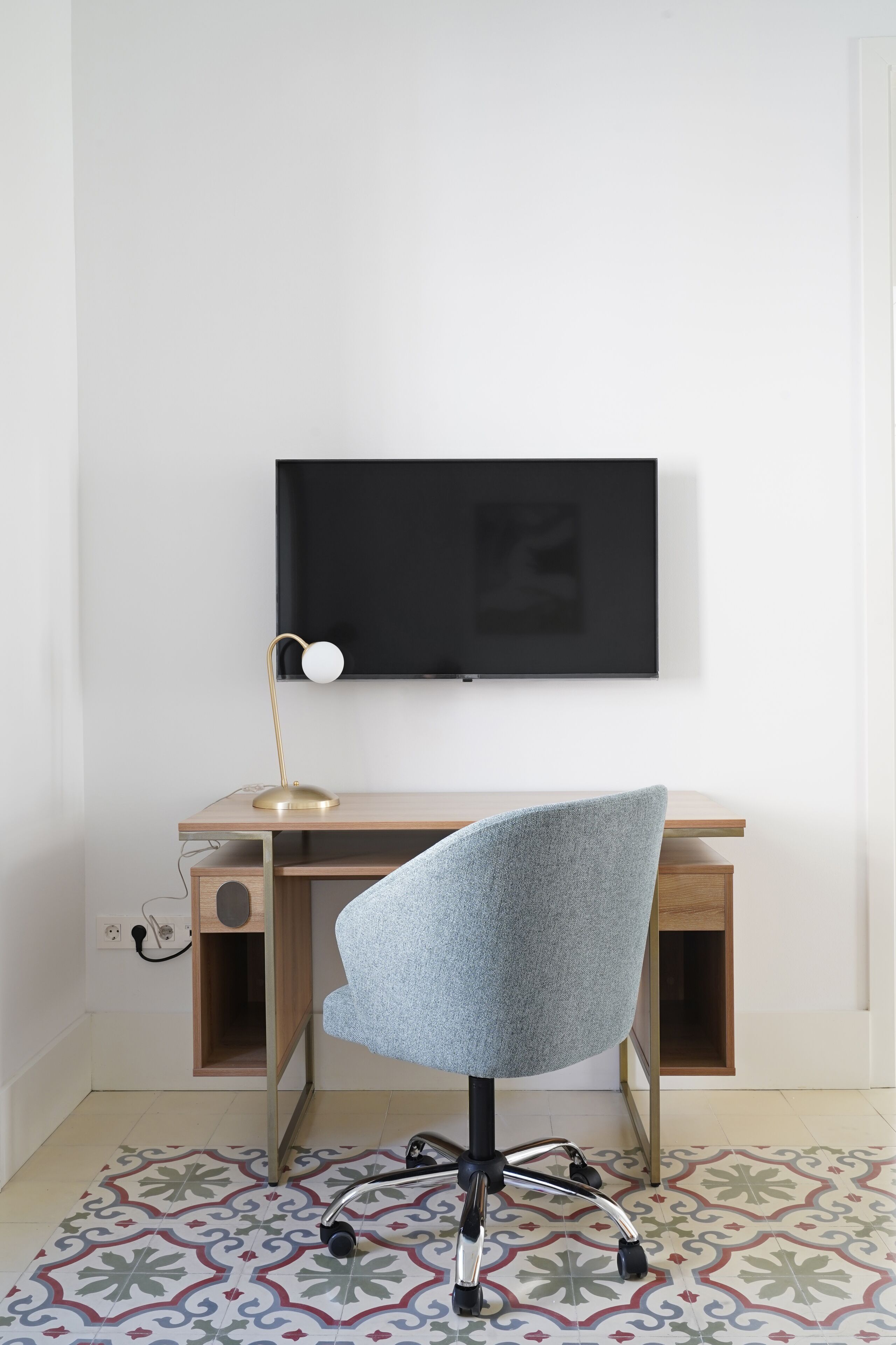 A modern workspace with a desk, chair, and mounted TV.