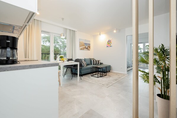 A modern living space with a kitchen area, a dining table, a sofa, and a coffee maker.