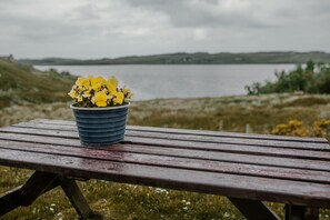 Une table de pique-nique en bois avec un pot bleu rempli de fleurs jaunes.