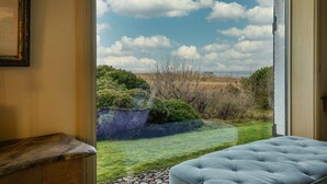 Ein Zimmer mit großem Fenster und Blick auf eine grüne Fläche mit Bäumen.