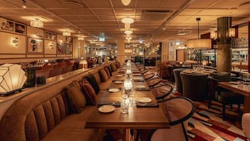 Una larga mesa de comedor con múltiples sillas, una zona de bar y un área de estar con bancos acolchados.