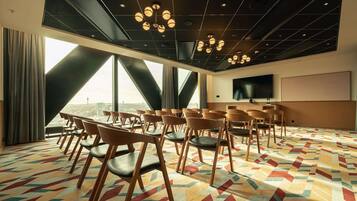 A conference room with a city view, large windows, a patterned carpet, and a flat-screen TV.