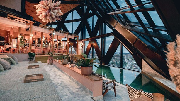 A modern interior with a large glass window, a seating area with cushions, and a view of the city. - Jacy'z Hotel & Resort (Gothenburg)