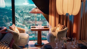 A room with a view of a cityscape, two armchairs, a small table with glasses and a book, and a lamp. - Jacy'z Hotel & Resort (Gothenburg)