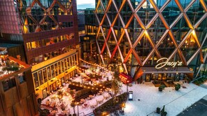 A modern building with a geometric facade and a well-lit outdoor seating area with tables and chairs. - Jacy'z Hotel & Resort (Gothenburg)