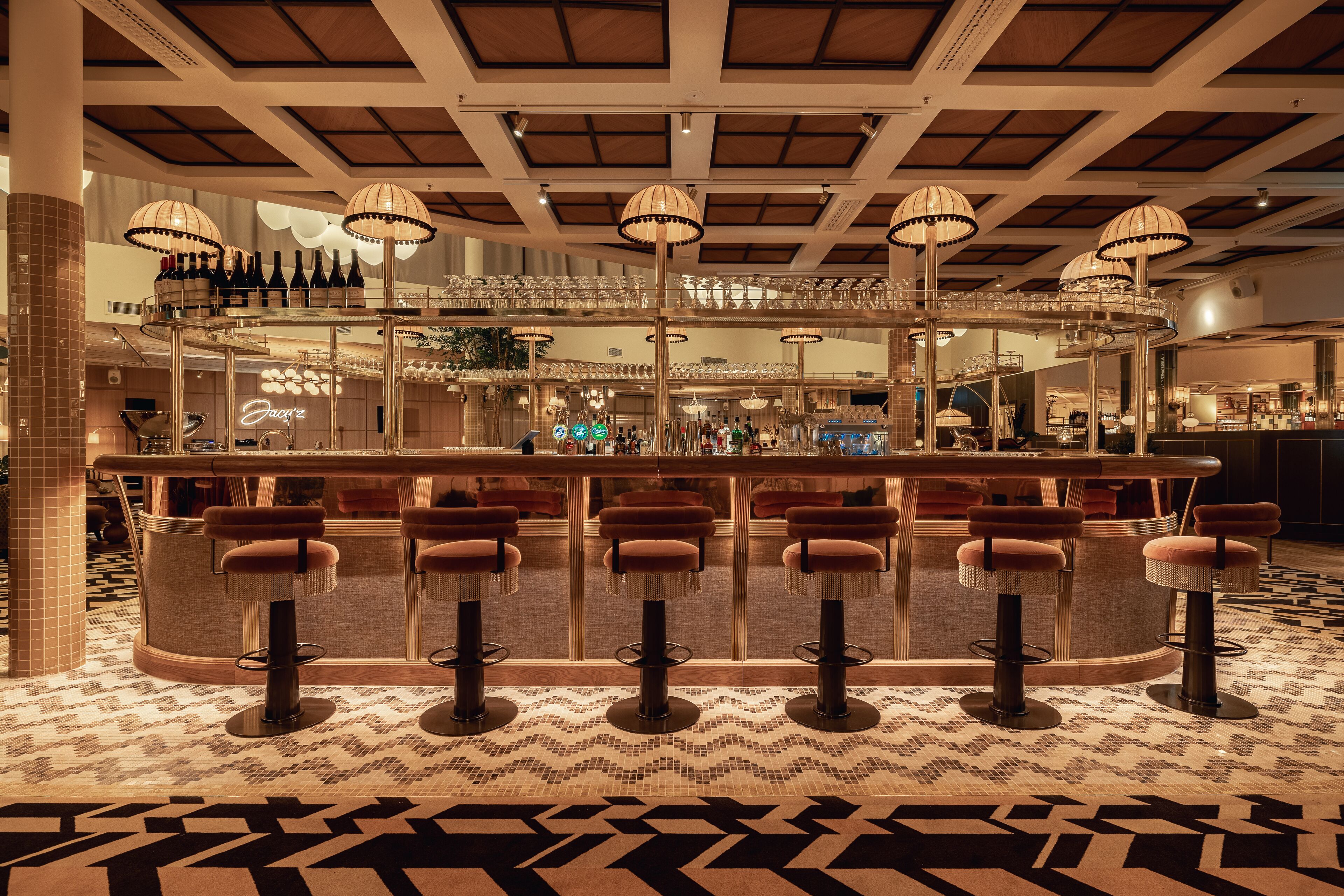 A bar area with multiple stools, a counter, and hanging lamps.