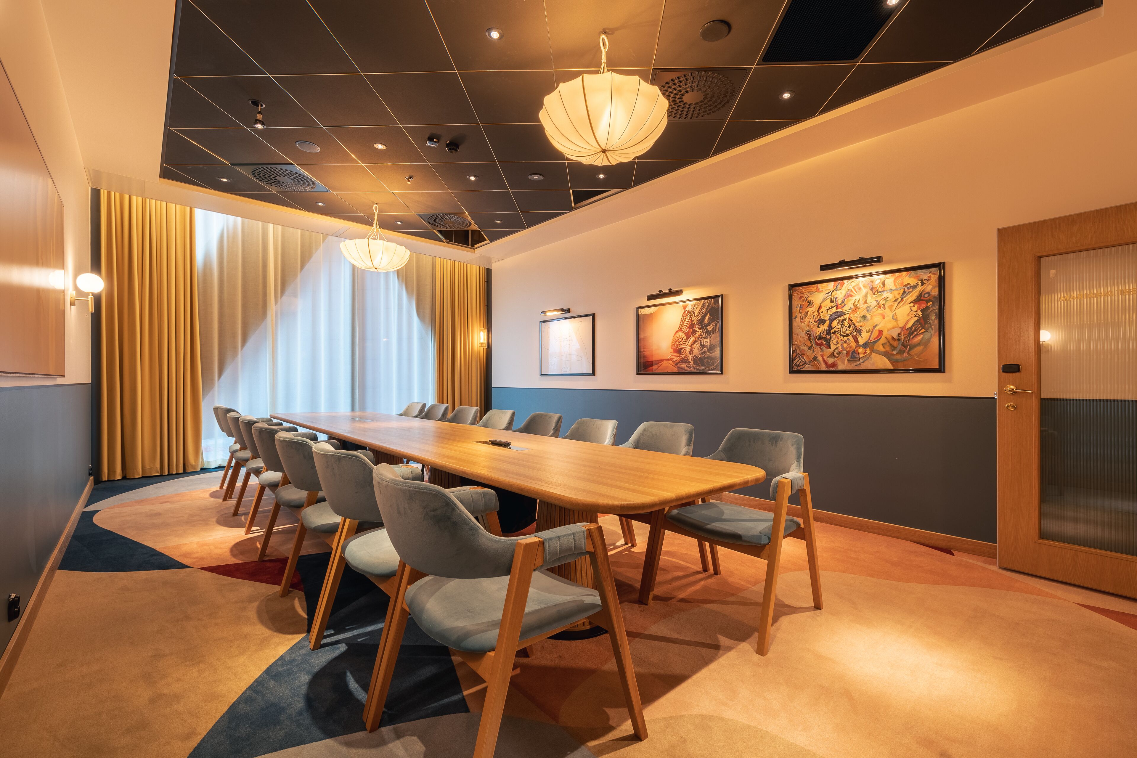 Un salón de conferencias con una larga mesa, varias sillas y un cuadro grande en la pared.