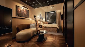 Una habitación de hotel moderna con sofá, una mesita redonda, cama y ventana grande.
