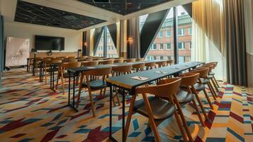 Une salle de conférence équipée d’une grande table, de chaises, d’un écran de télévision et d’un tapis à motifs.