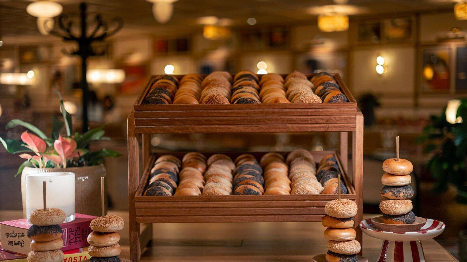 A wooden display stand with various baked goods, including bread and pastries, in a cozy bakery setting.