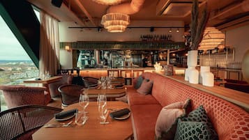 Un restaurant doté d’un bar, de tables et offrant une vue sur la ville.
