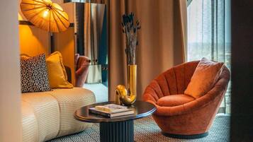 A modern living room with a sofa, a round coffee table, and a unique orange armchair.