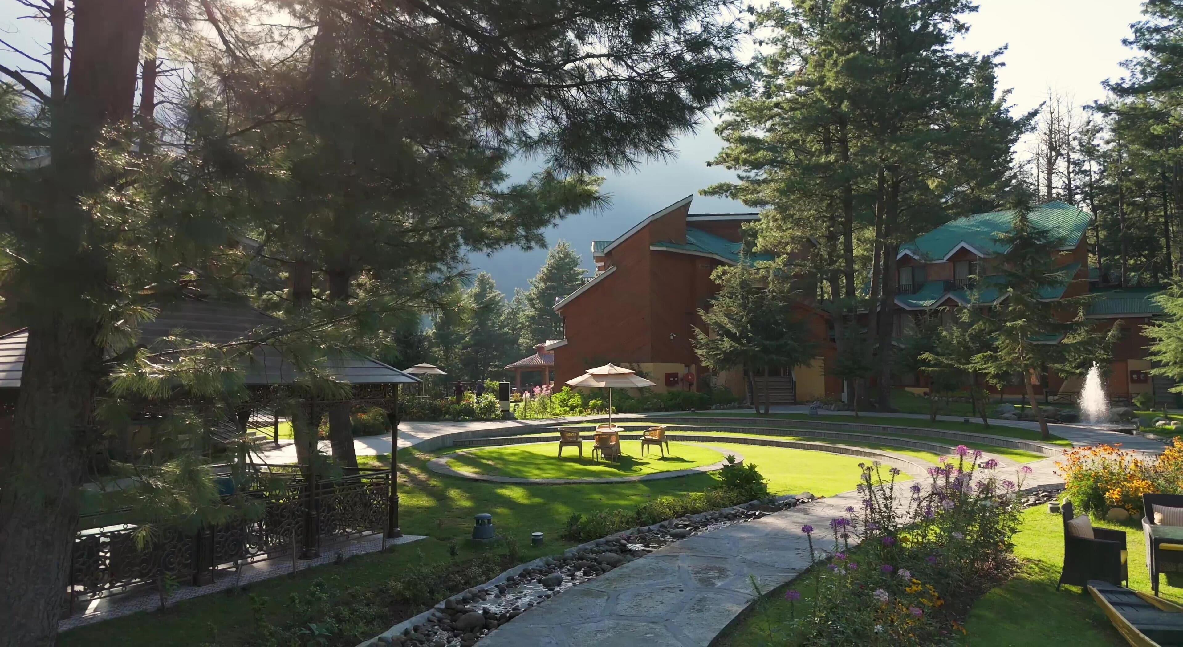A resort with a central lawn, outdoor seating, and a building with a green roof.