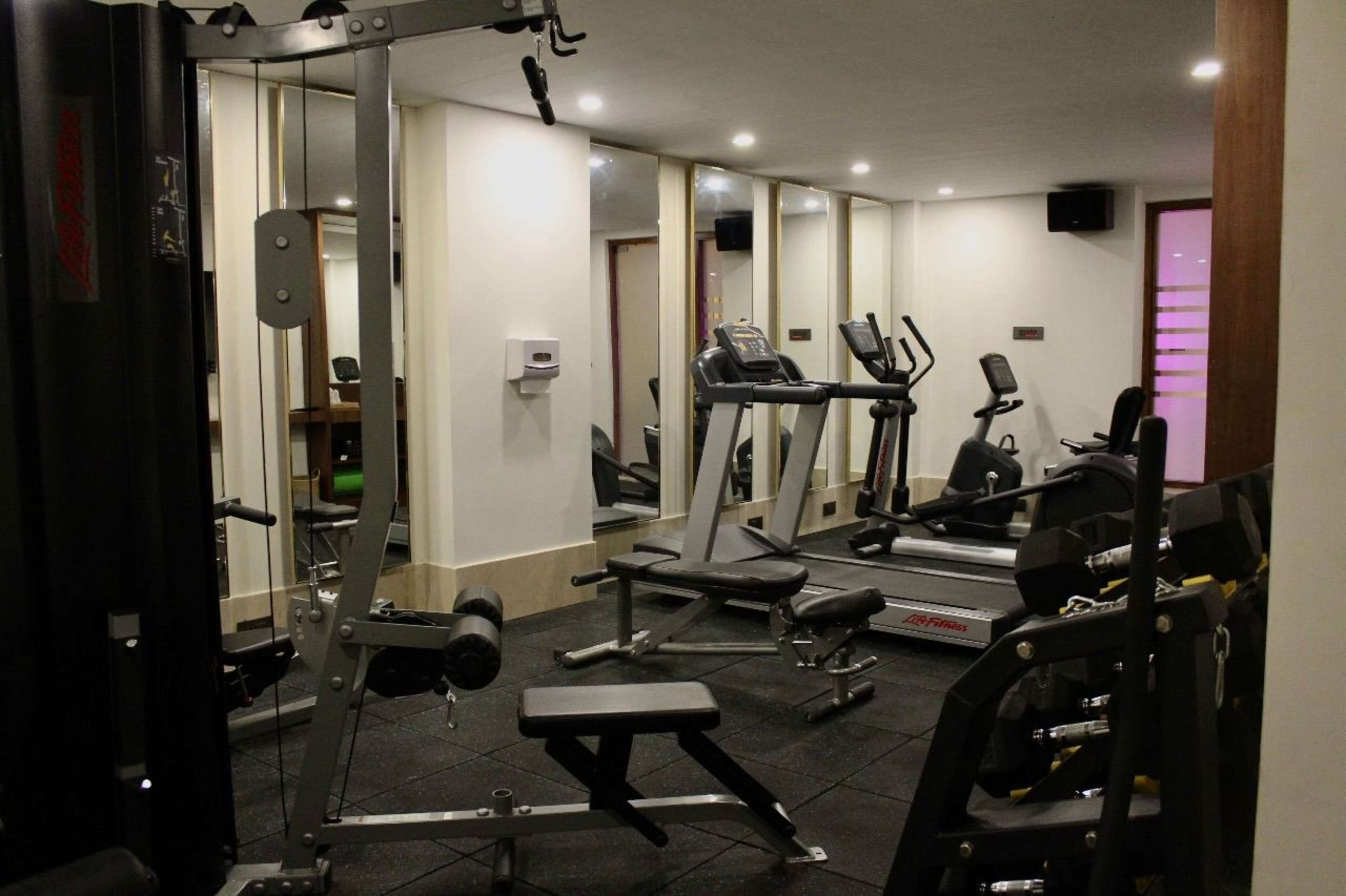 A gym with various exercise equipment including treadmills, weight machines, and free weights.