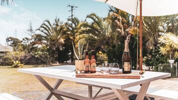 An outdoor table with a bottle of Chandon wine, two Stone Wood Pacific Ale bottles, and glasses.