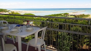 A dining table with chairs on a balcony overlooking a beach and the sea. - Studio with amazing views-Beahost (Porto Santa Margherita)