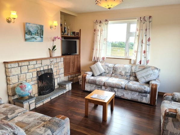 A living room with a stone fireplace, a sofa, a coffee table, and a television.