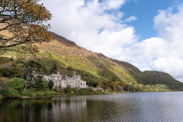 A castle by a lake with a mountainous backdrop.