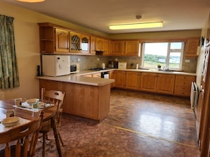 A kitchen with wooden cabinets, a central island, and a dining table with chairs.