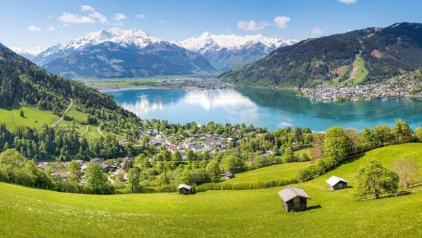 A scenic view of a lake surrounded by mountains and a small village with houses and greenery. - House no More for Rent (Zell am See)