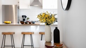 Une cuisine avec un vase blanc contenant des fleurs jaunes, posé sur une table en bois.