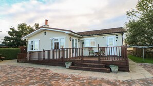 Ein zweistöckiges Haus mit Ziegelterrasse, Holzterrasse und umzäunter Garten.
