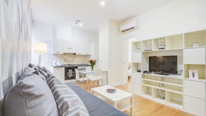 Un salon moderne avec un canapé, une table basse et un téléviseur posé sur un meuble de télévision blanc.