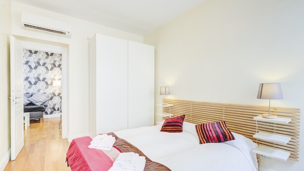 Une chambre d’hôtel moderne avec un lit bien fait, une table de chevet avec une lampe et une armoire.
